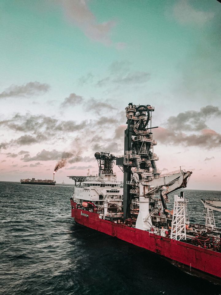 Navio de apoio offshore em alto-mar com plataforma ao fundo